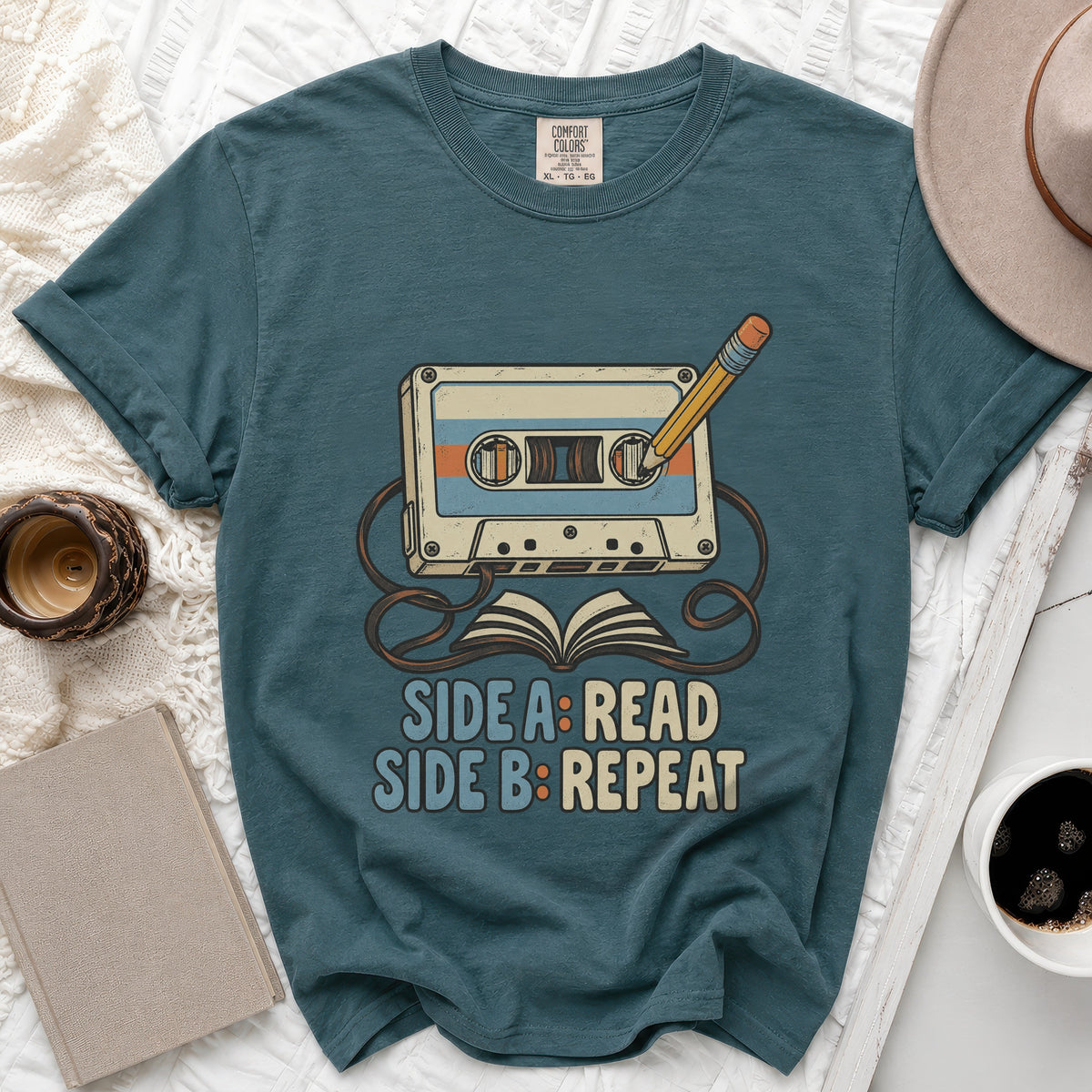 Teal t-shirt with cassette tape, pencil, and book graphic reading "Side A: Read Side B: Repeat."