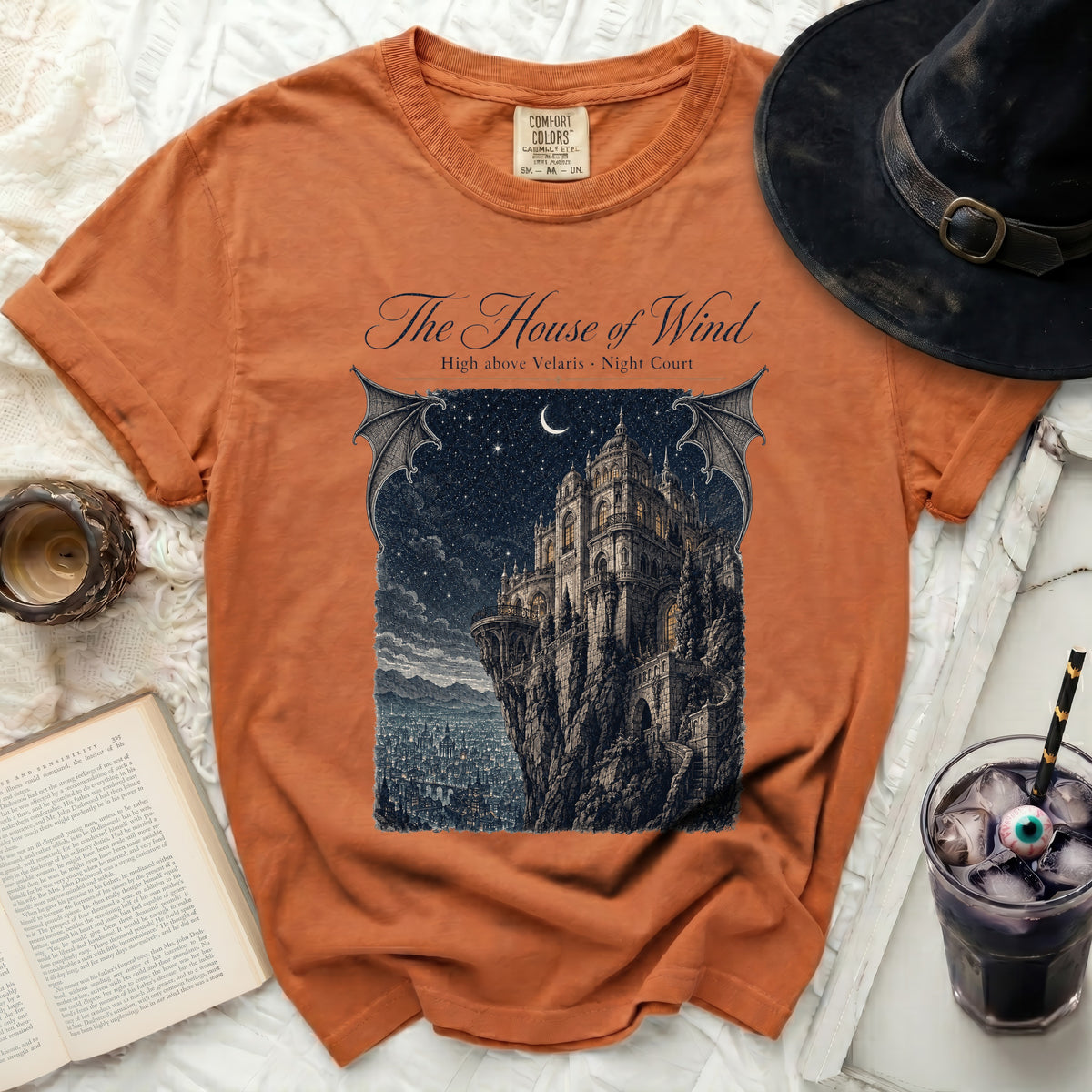 Orange t-shirt with "The House of Wind" graphic of a castle on a cliff.
