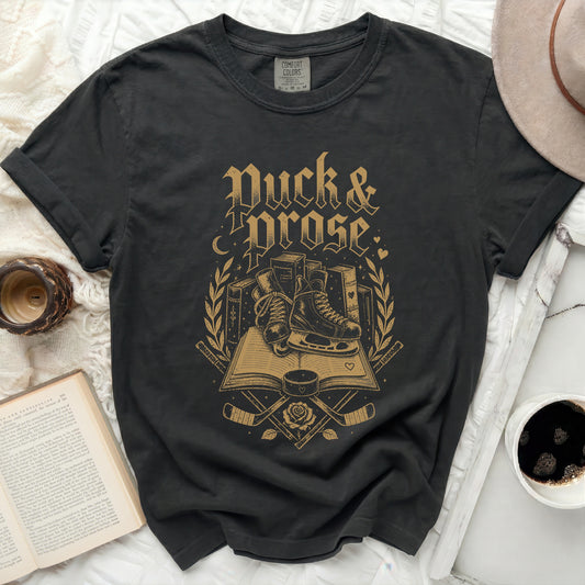 Black t-shirt with gold "Duck & Prose" text, books, and hockey skates.