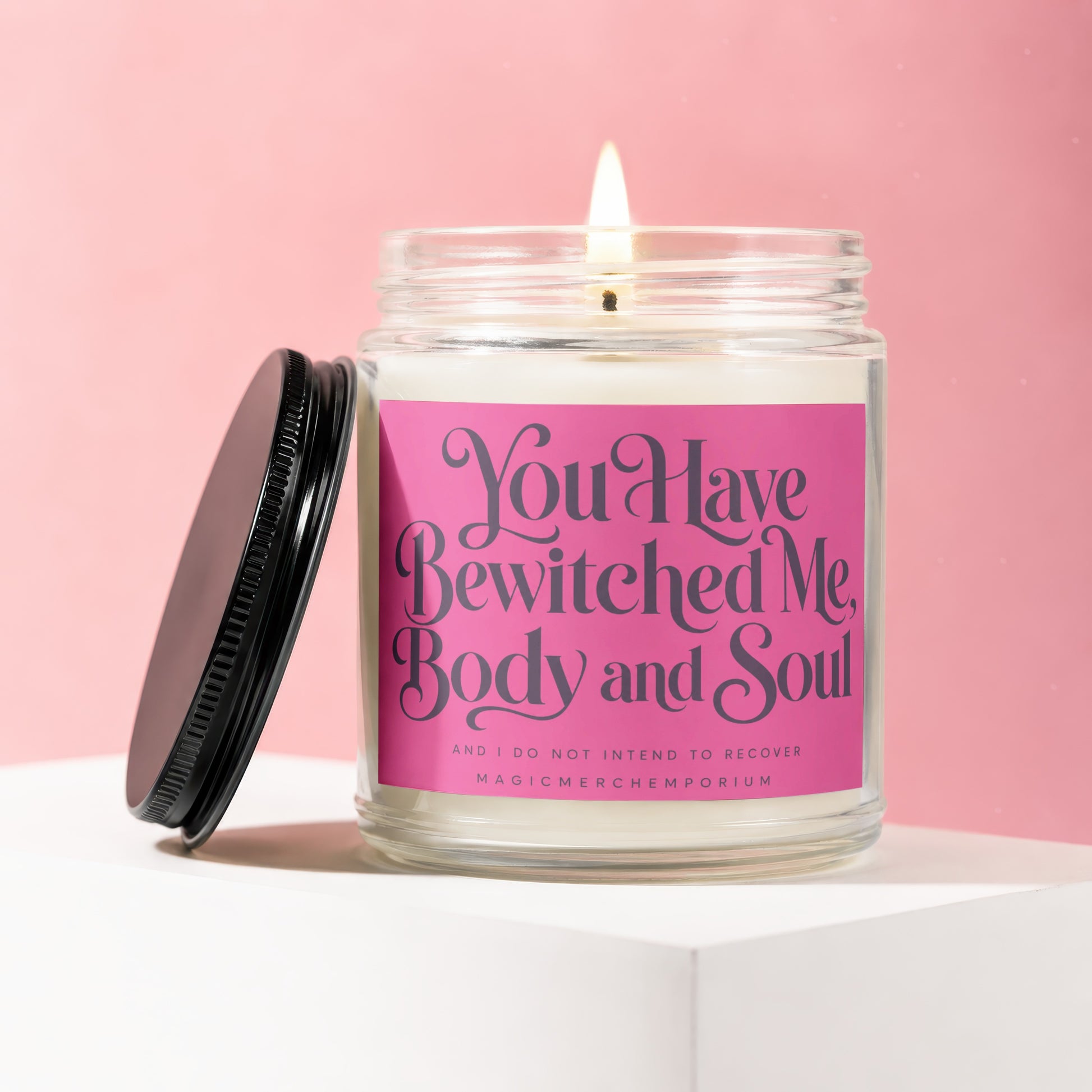 Jar candle on white surface with pink background, text reads "You Have Bewitched Me, Body and Soul".