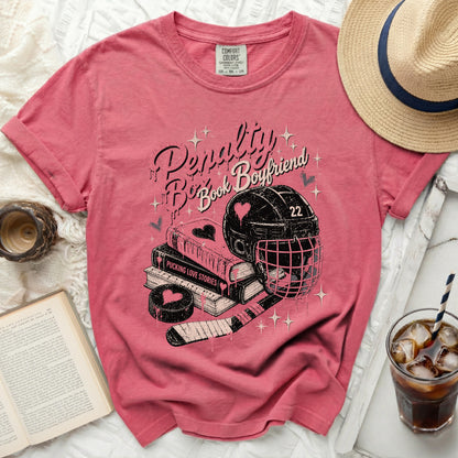 Pink t-shirt with "Penalty Book Boyfriend" text, hockey puck, stick, and helmet.