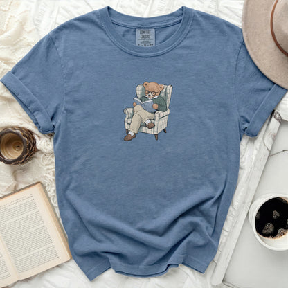 Blue t-shirt with a graphic of a bear reading in a chair.