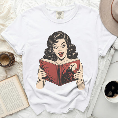 White t-shirt with a vintage comic graphic of a surprised woman reading a spooky book.