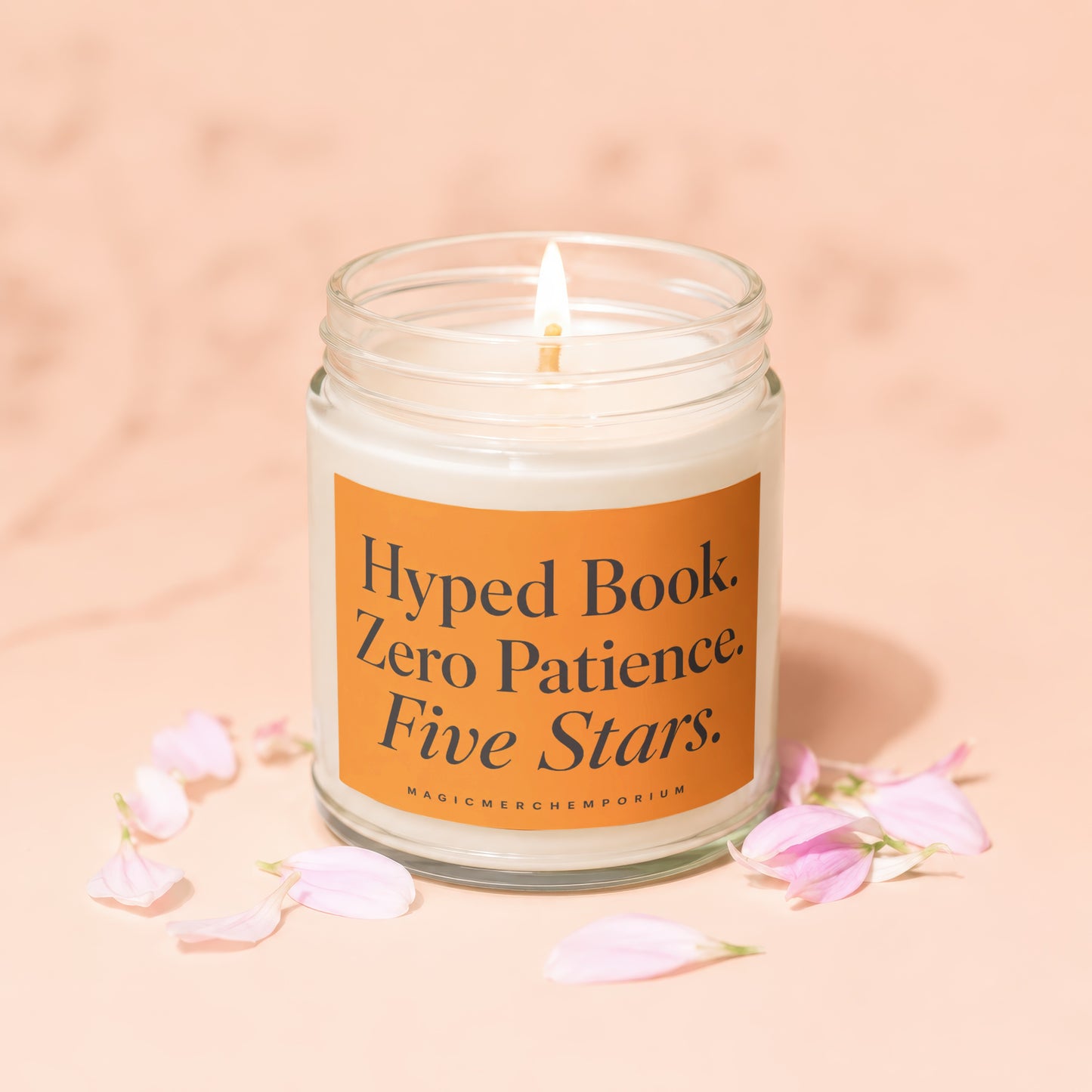 Lit candle in glass jar with orange label reading "Hyped Book. Zero Patience. Five Stars."
