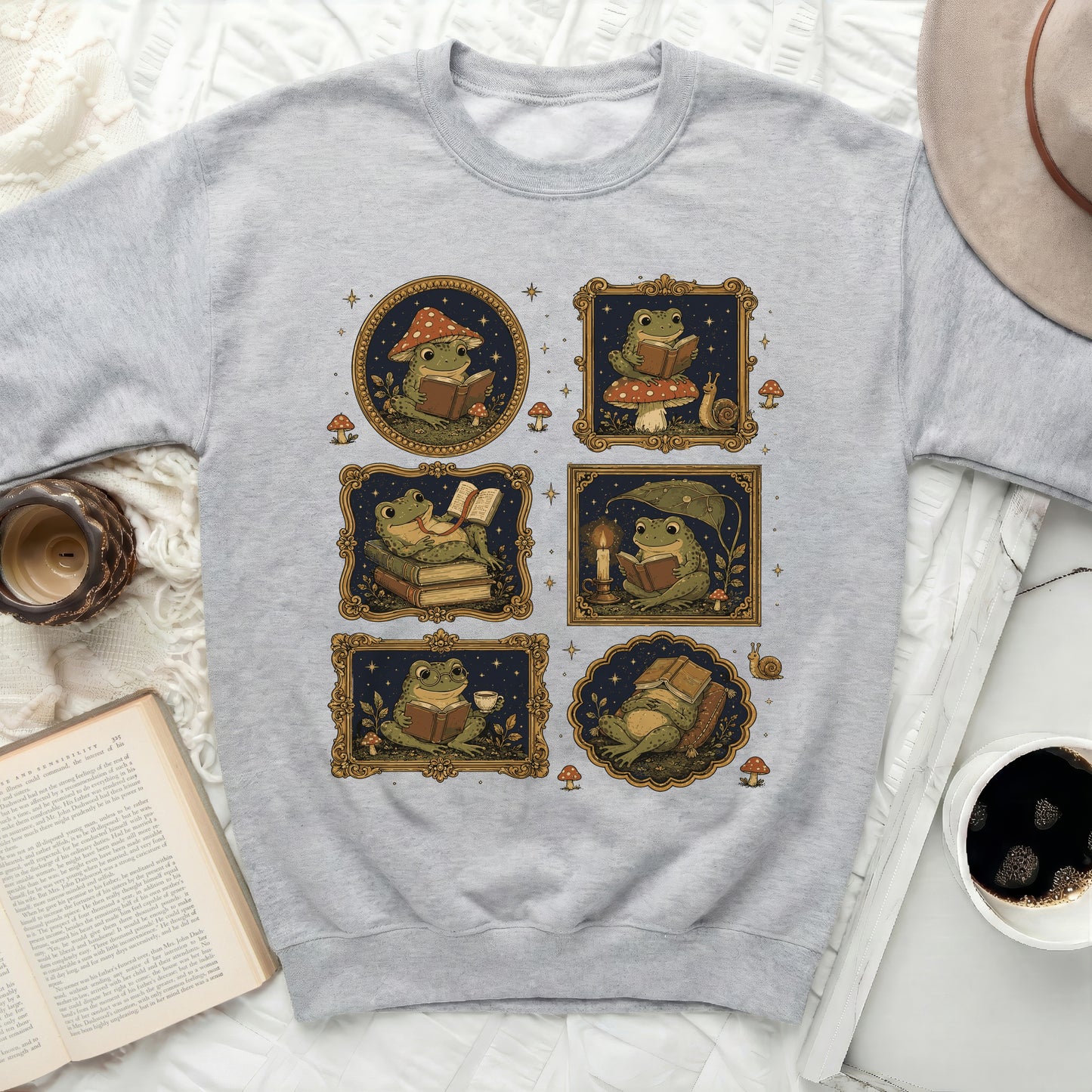 Six vintage-style frames on a gray sweatshirt feature illustrated frogs reading books.
