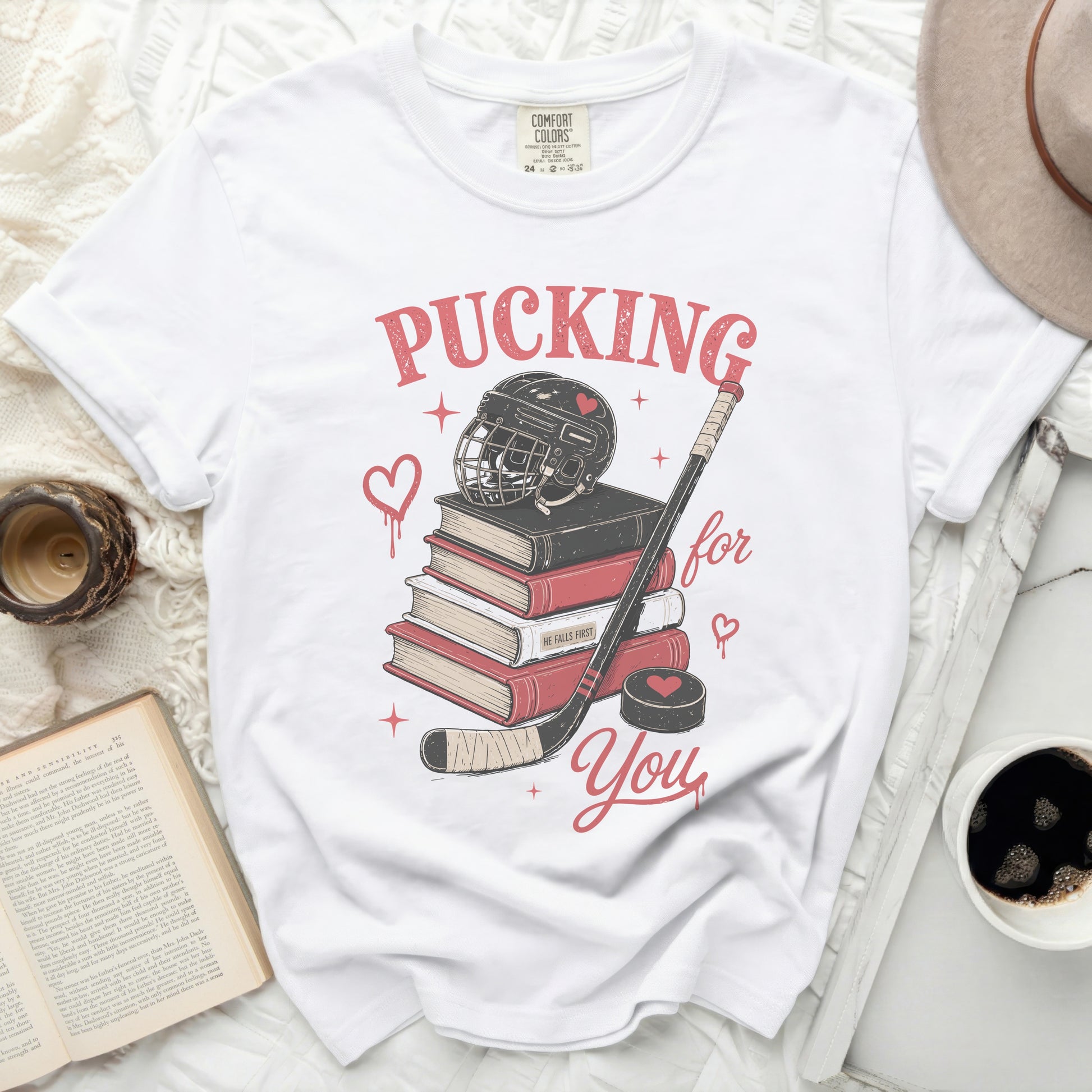 White t-shirt with "Pucking for You" and hockey graphics on books.