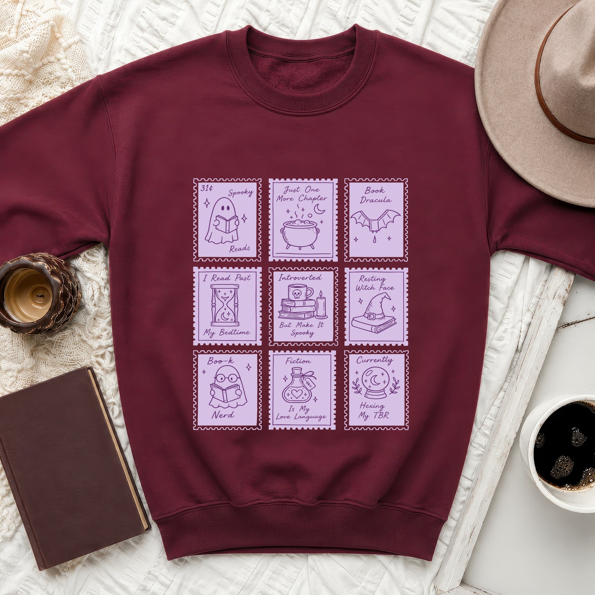 Maroon sweatshirt with purple stamp-like graphics of books, ghosts, and witches.