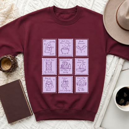 Maroon sweatshirt with purple stamp-like graphics of books, ghosts, and witches.