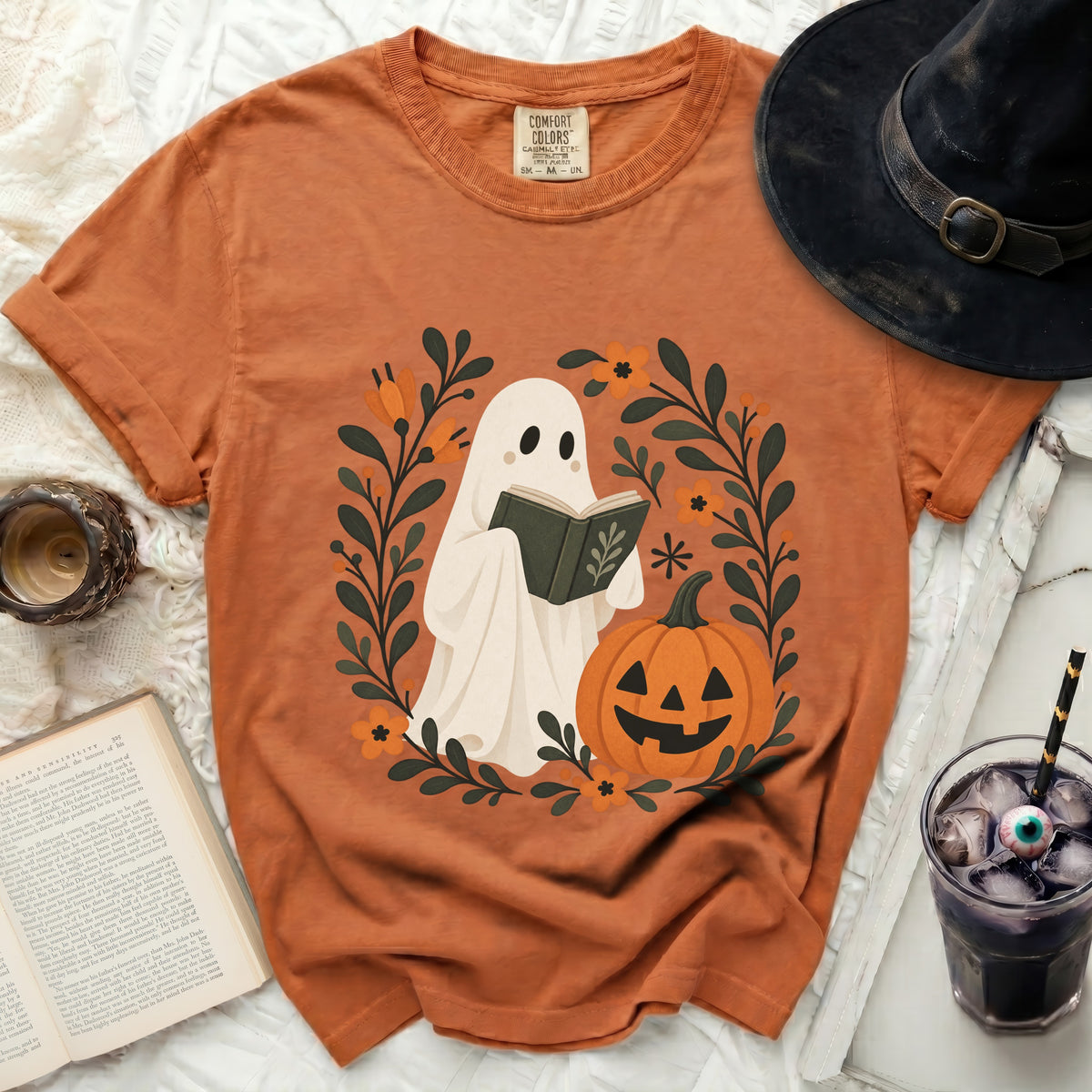 Orange t-shirt with ghost reading a book, pumpkin, and floral design.