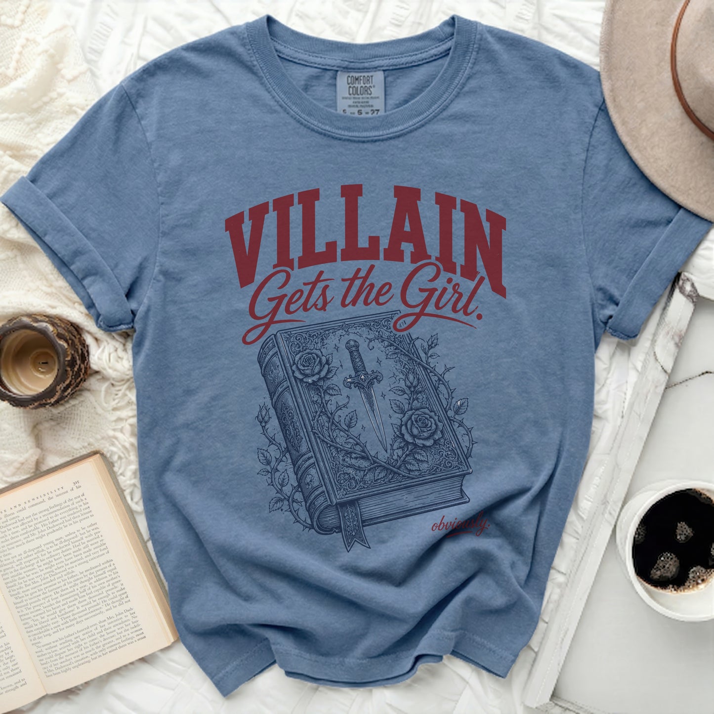 Blue t-shirt with "VILLAIN Gets the Girl." text over a book and dagger.
