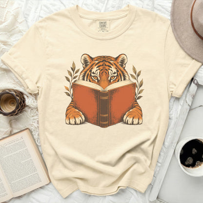 Tiger reading an open book with leaves, printed on a tan t-shirt.