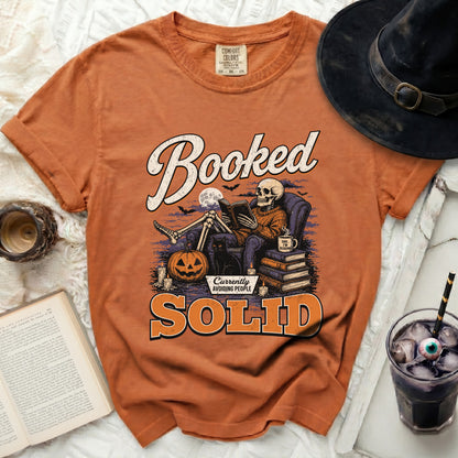 Orange t-shirt with a skeleton reading a book, Halloween theme text