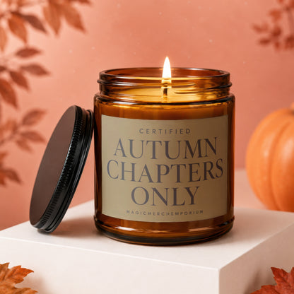 Amber glass candle with lid off, lit flame, and "Autumn Chapters Only" text.