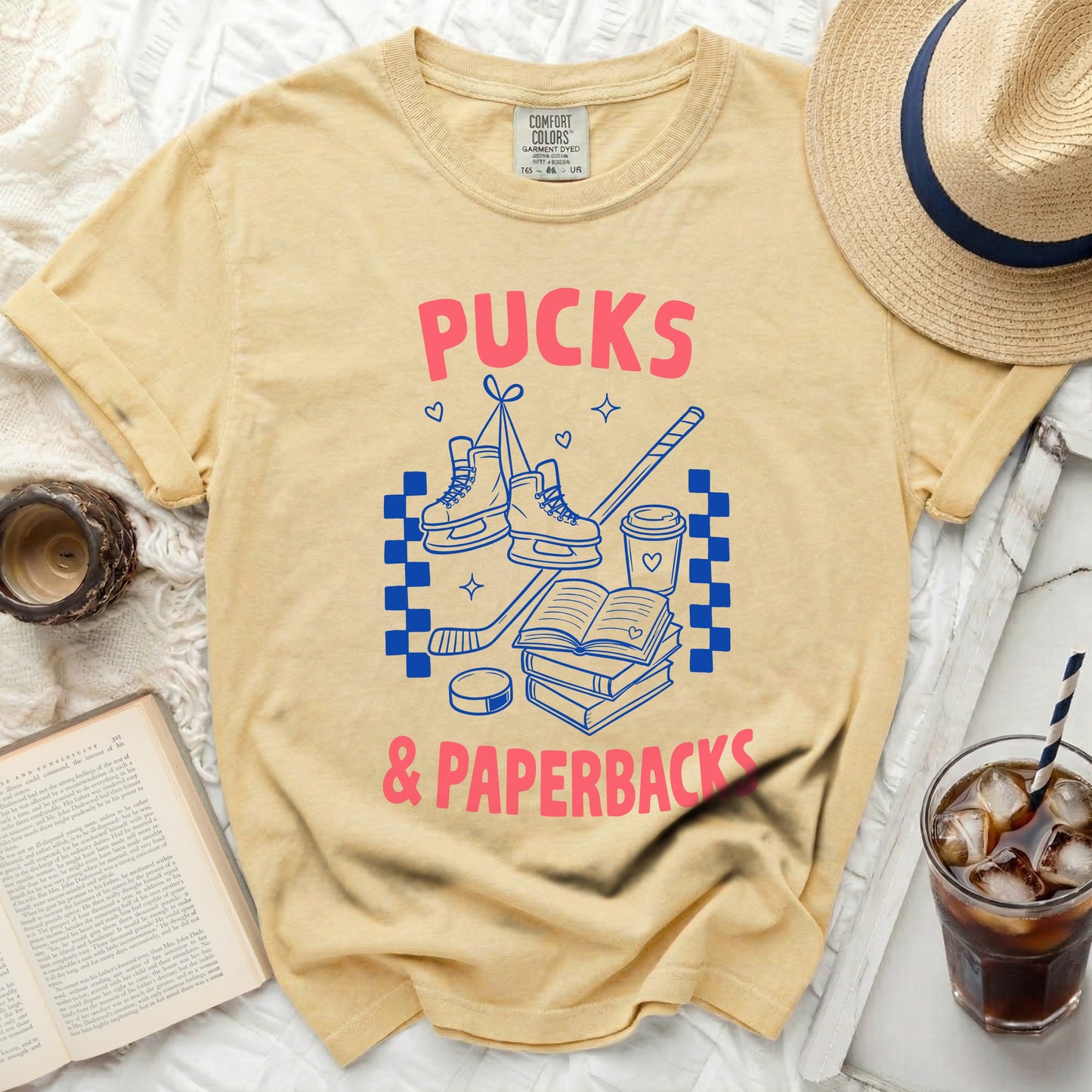 Yellow t-shirt with "Pucks & Paperbacks" text, hockey skates, and books.