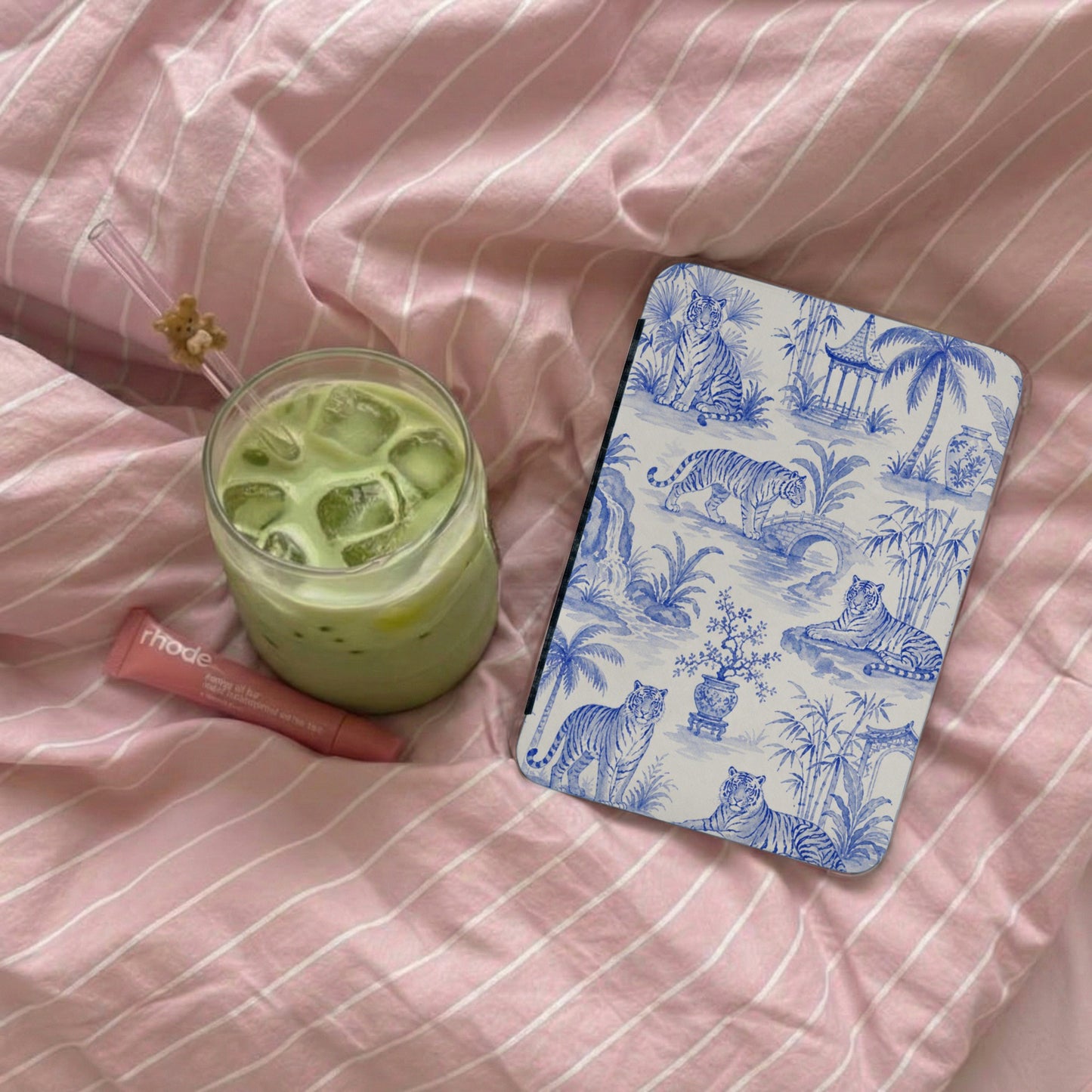 Green matcha drink next to a cosmetic tube and a device with blue tiger pattern.