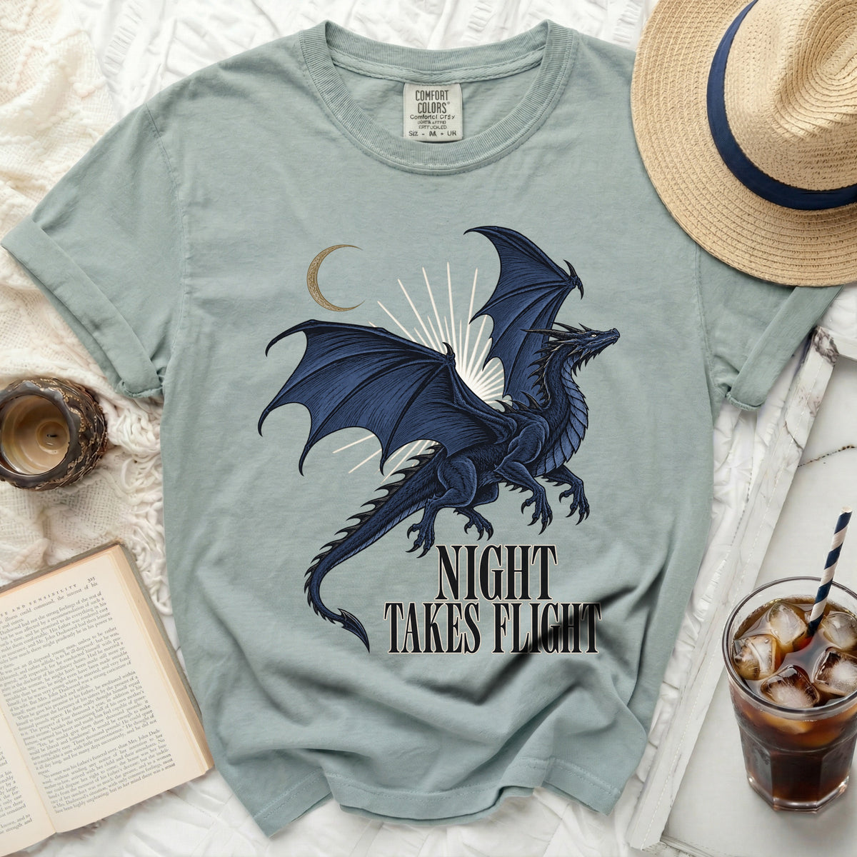 Light blue t-shirt with a dark blue dragon and moon graphic, reading "Night Takes Flight".