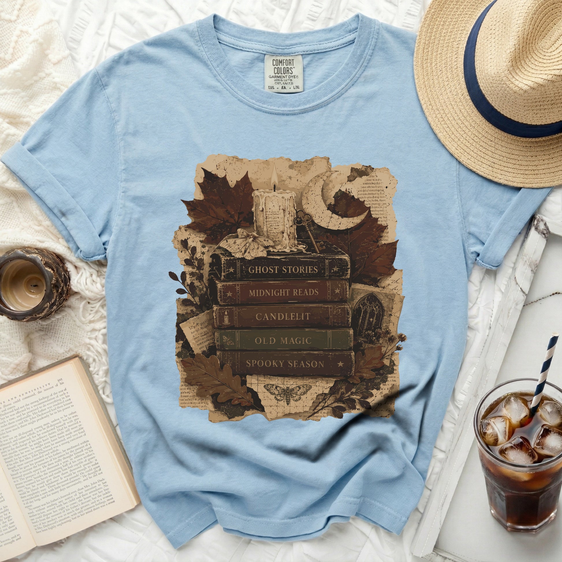 Light blue t-shirt with stacked books featuring fall imagery and text.