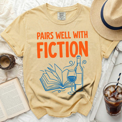 Yellow t-shirt with "Pairs Well With Fiction" text and book illustration.