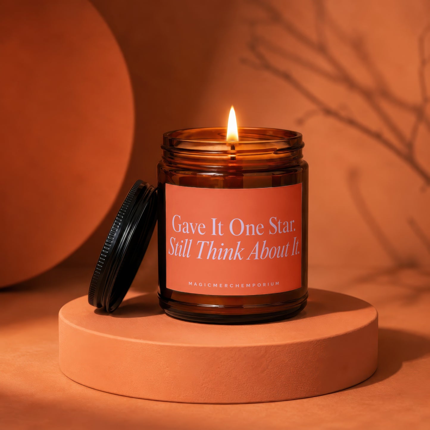 Burning glass candle with orange label stating "Gave It One Star. Still Think About It."