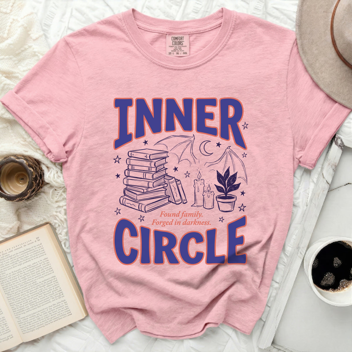 Pink t-shirt with "INNER CIRCLE" and dark illustrations of books, bats, and candles.