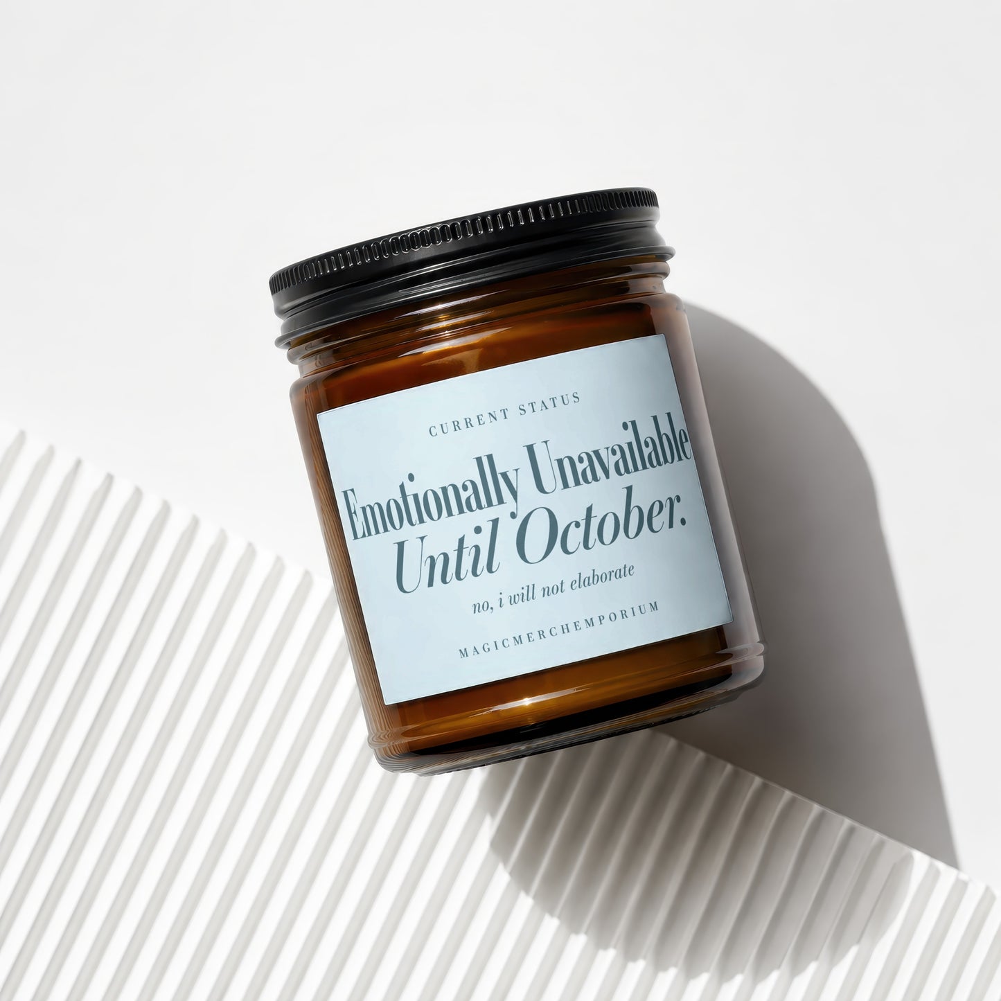 Brown glass candle with black lid and label reading "Emotionally Unavailable Until October."