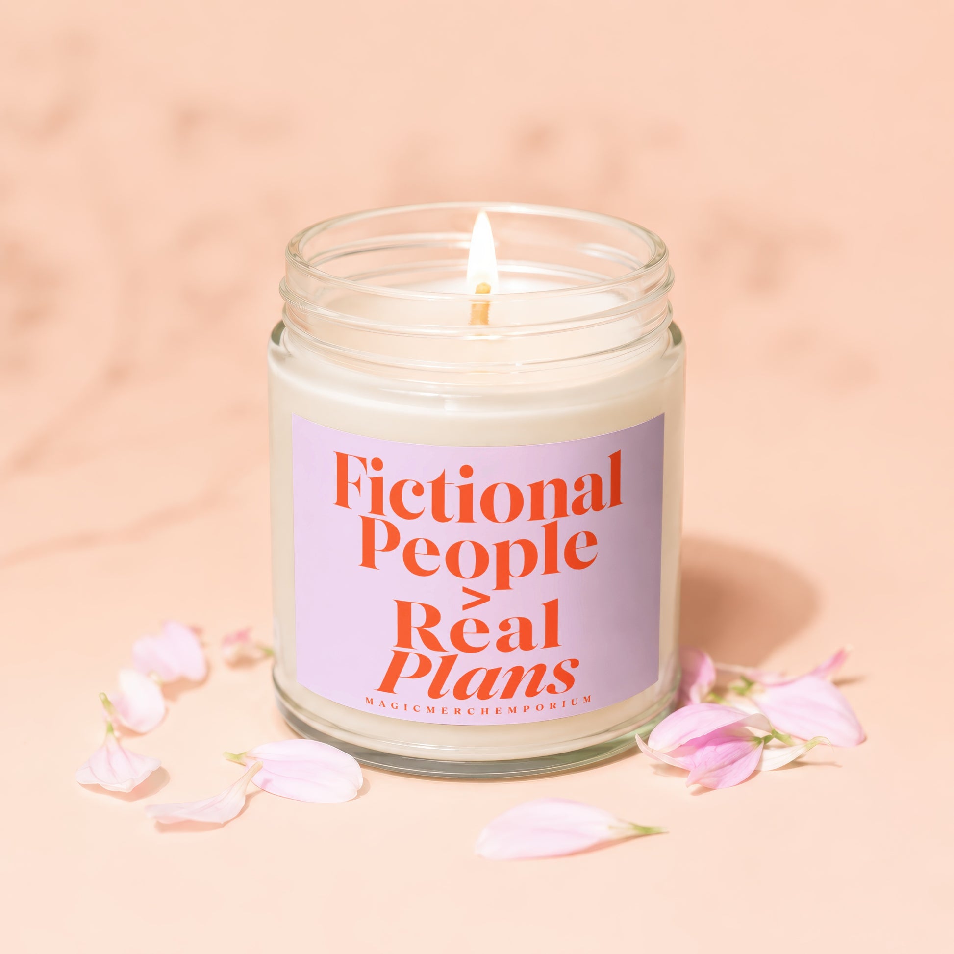 Candle with text "Fictional People Real Plans" and "MAGICMERCHEPORIUM" on a pink background.