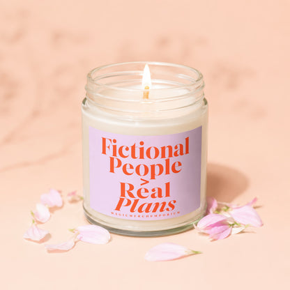 Candle with text "Fictional People Real Plans" and "MAGICMERCHEPORIUM" on a pink background.