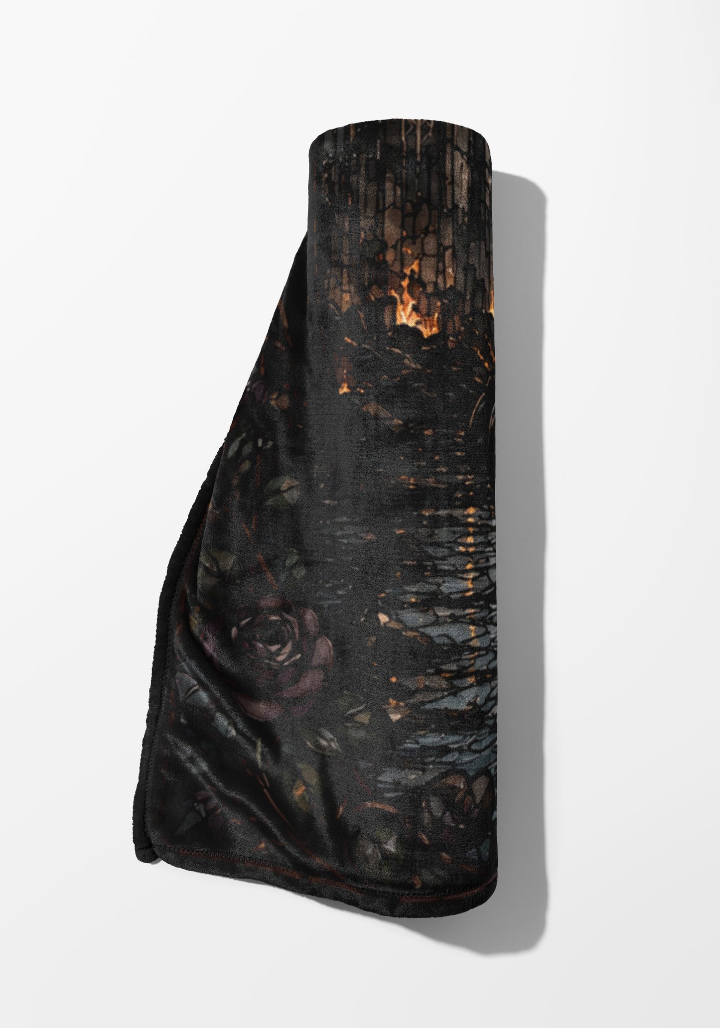 Rolled dark blanket with a rose and burning wood pattern.
