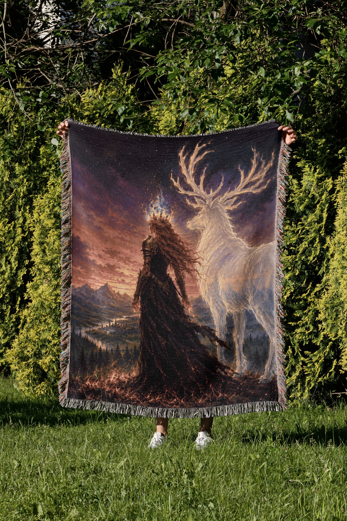 A person is holding up a large tapestry or blanket with a painting of a woman in a long black dress standing in a forest, with a white deer-like creature in the background.