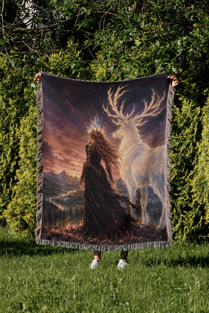 A person is holding up a large tapestry or blanket with a painting of a woman in a long black dress standing in a forest, with a white deer-like creature in the background.