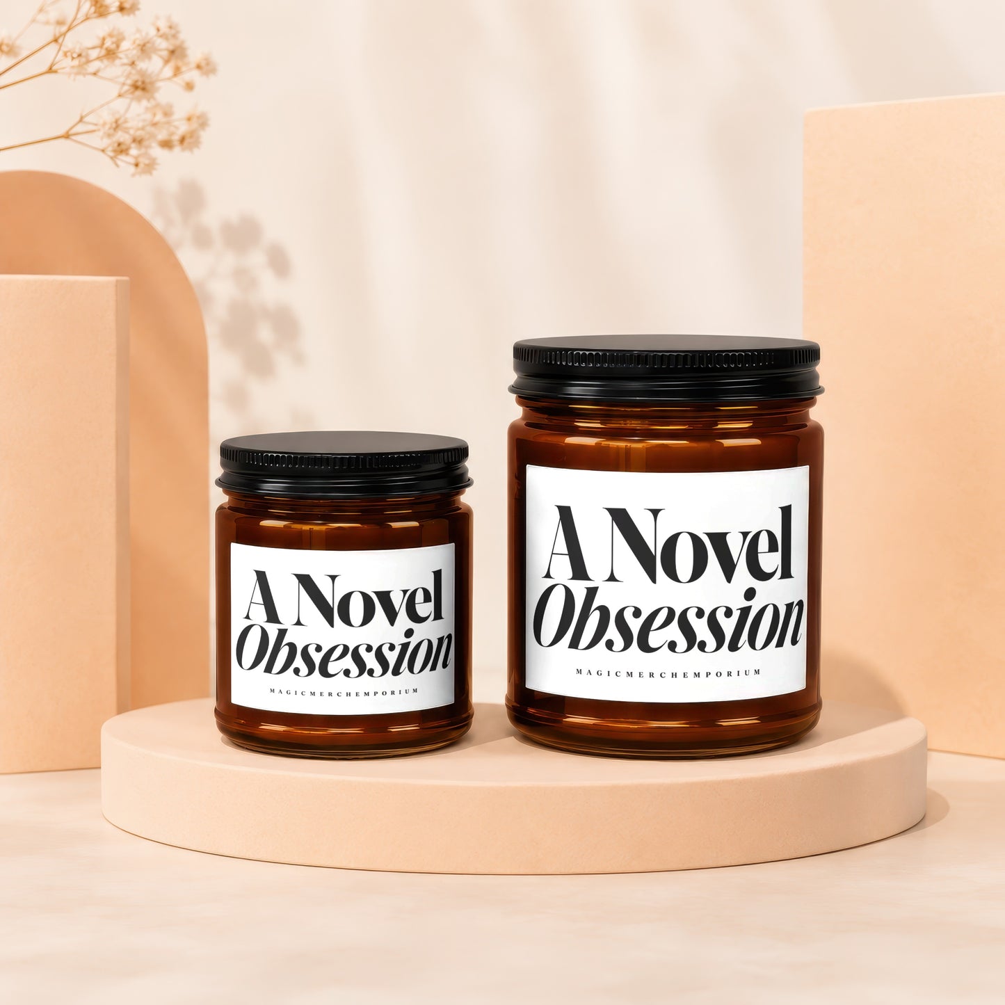 Two amber glass candles with white labels reading "A Novel Obsession" and "MAGICMERCHEMPORIUM".