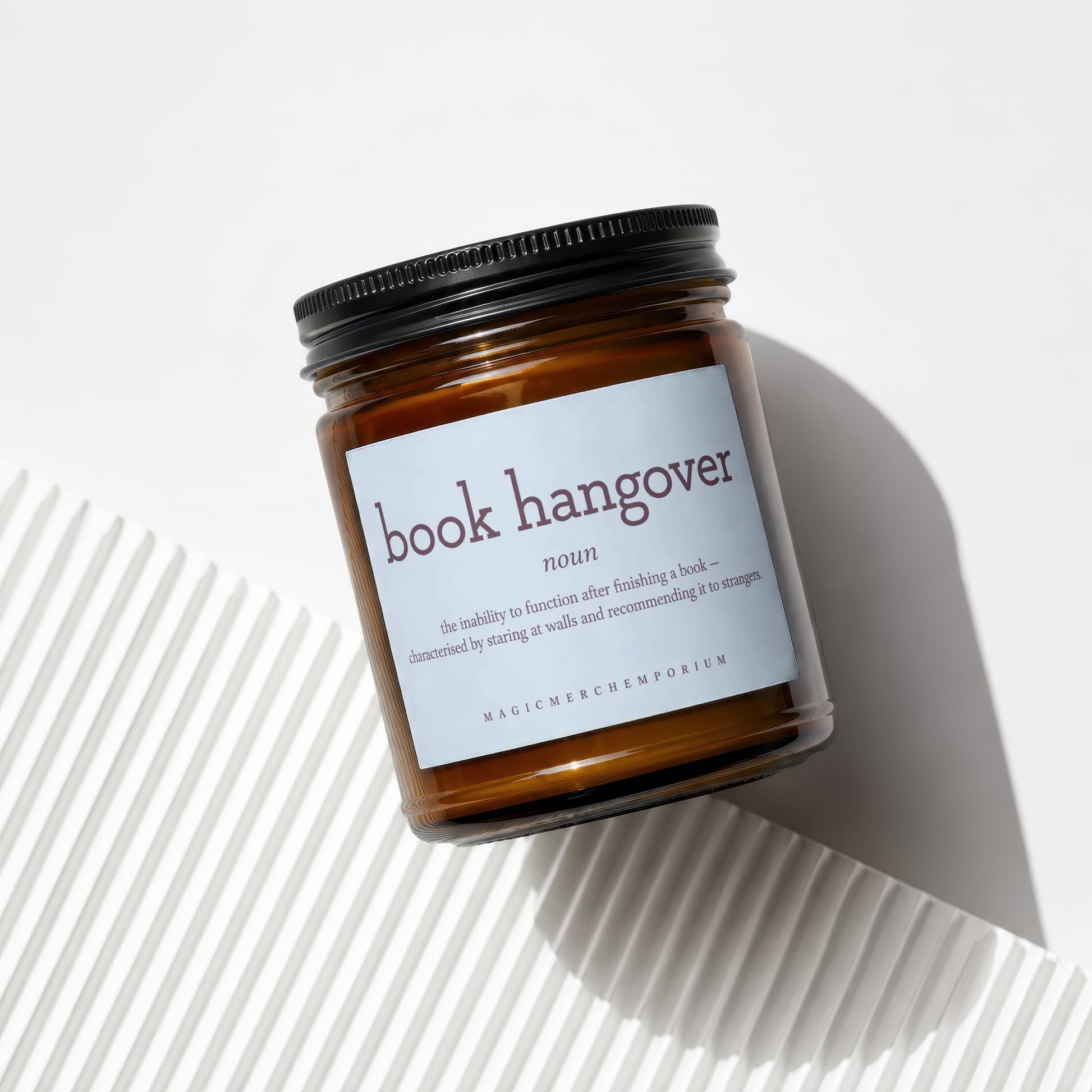 Amber jar candle with "book hangover" definition and Magic Merch Emporium logo.