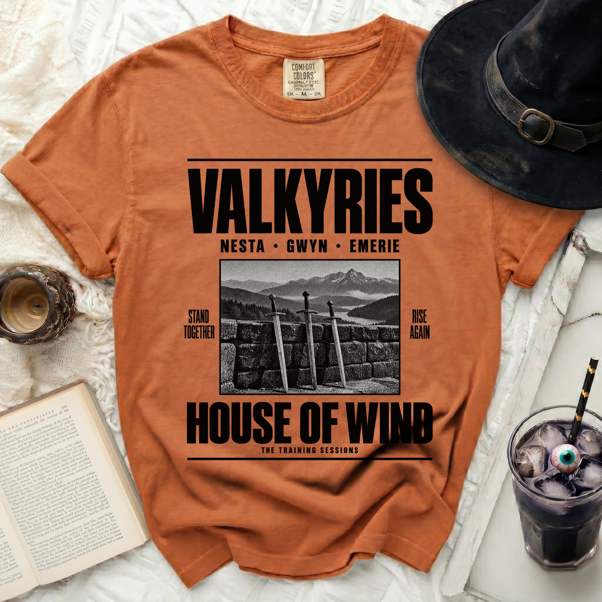 Orange t-shirt with "VALKYRIES" and "HOUSE OF WIND" text, swords, and mountains.