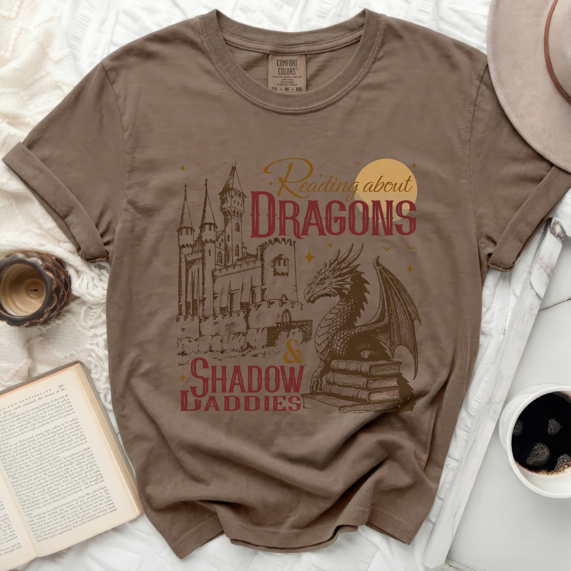 Brown t-shirt with "Reading about DRAGONS & SHADOW DADDIES" graphic.