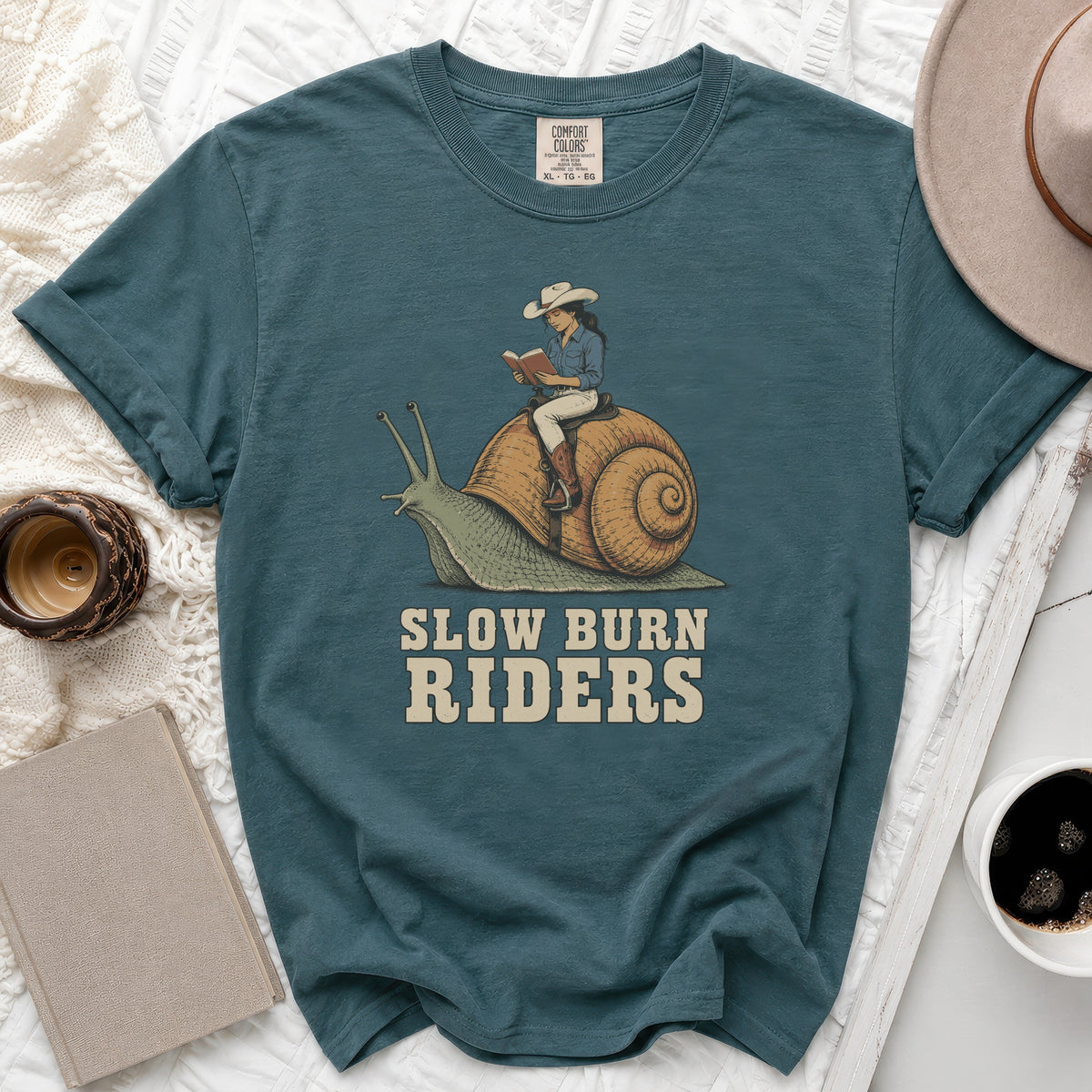 Teal t-shirt with graphic of woman on snail, reading, text "SLOW BURN RIDERS".