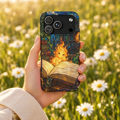 A hand holds a smartphone featuring a stained-glass design of a cute fire sprite on an open book.