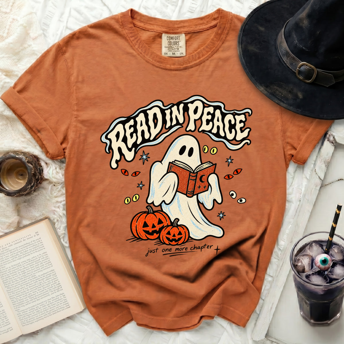 Orange t-shirt with a ghost reading a book, pumpkins, and "READ IN PEACE" text.
