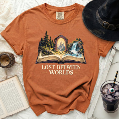 Orange t-shirt with "Lost Between Worlds" text and a castle scene from an open book.