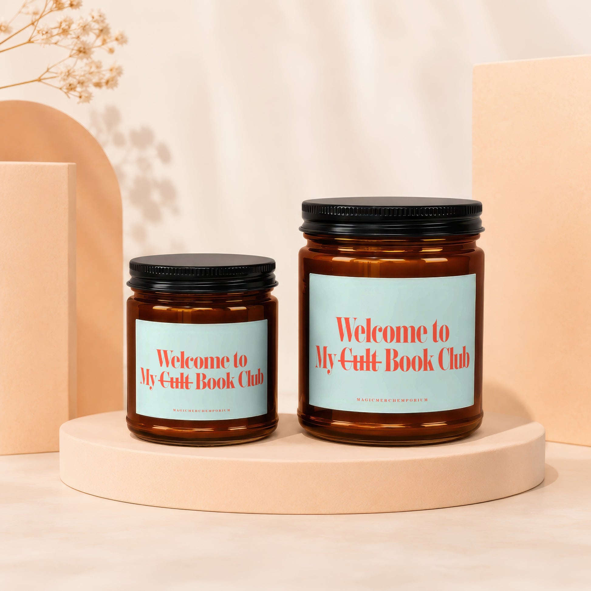 Two amber glass candles with black lids, labeled "Welcome to My Cult Book Club".