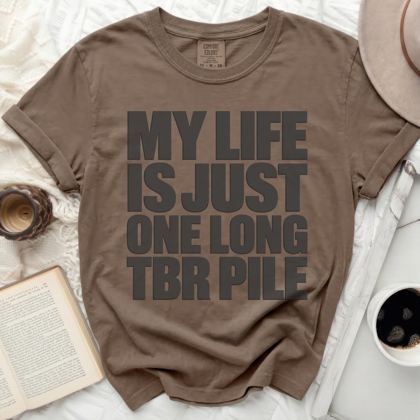 Brown t-shirt with large gray text "MY LIFE IS JUST ONE LONG TBR PILE".