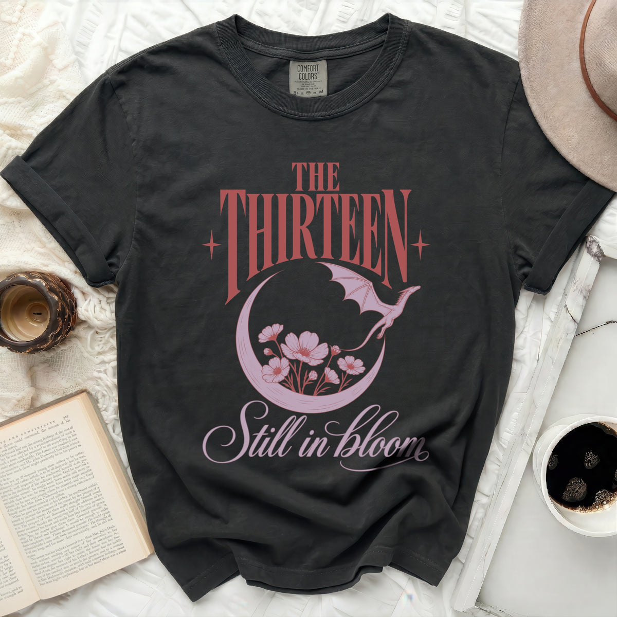 Dark grey t-shirt with "The Thirteen" and "Still in bloom" text and dragon design.