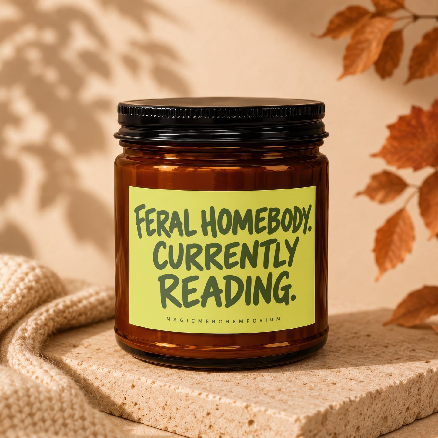 Brown glass candle with yellow label reading "Feral Homebody Currently Reading."