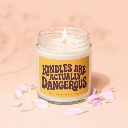 Candle with "Kindles are actually dangerous" text on yellow label, surrounded by pink petals.