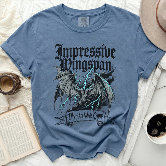 Blue t-shirt with graphic of dragon wings, lightning, and text "Impressive Wingspan Illyrian WAR CAMP".