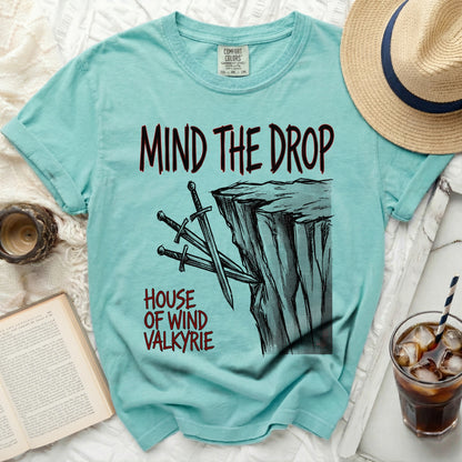 Teal t-shirt with "Mind the Drop" and "House of Wind Valkyrie" graphic.