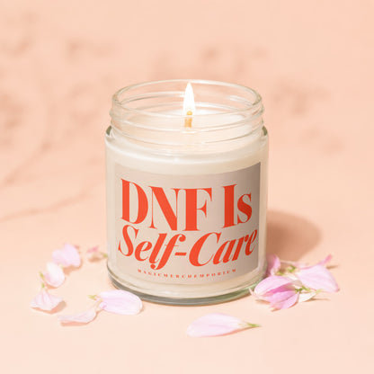 Jar candle with lit wick and "DNF Is Self-Care" text surrounded by pink petals.