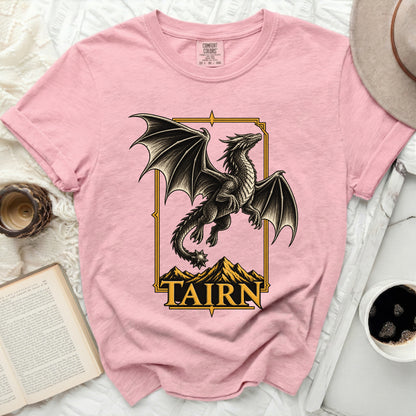 Pink t-shirt with a black dragon graphic and the word "TAIRN" below mountains.