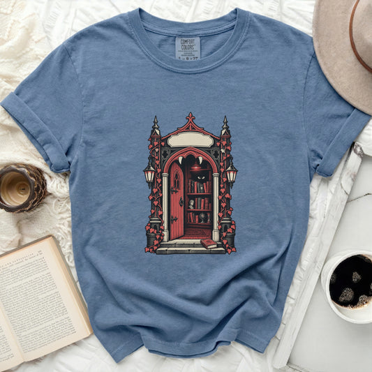 Blue t-shirt with gothic door and bookshelf graphic, featuring fangs.