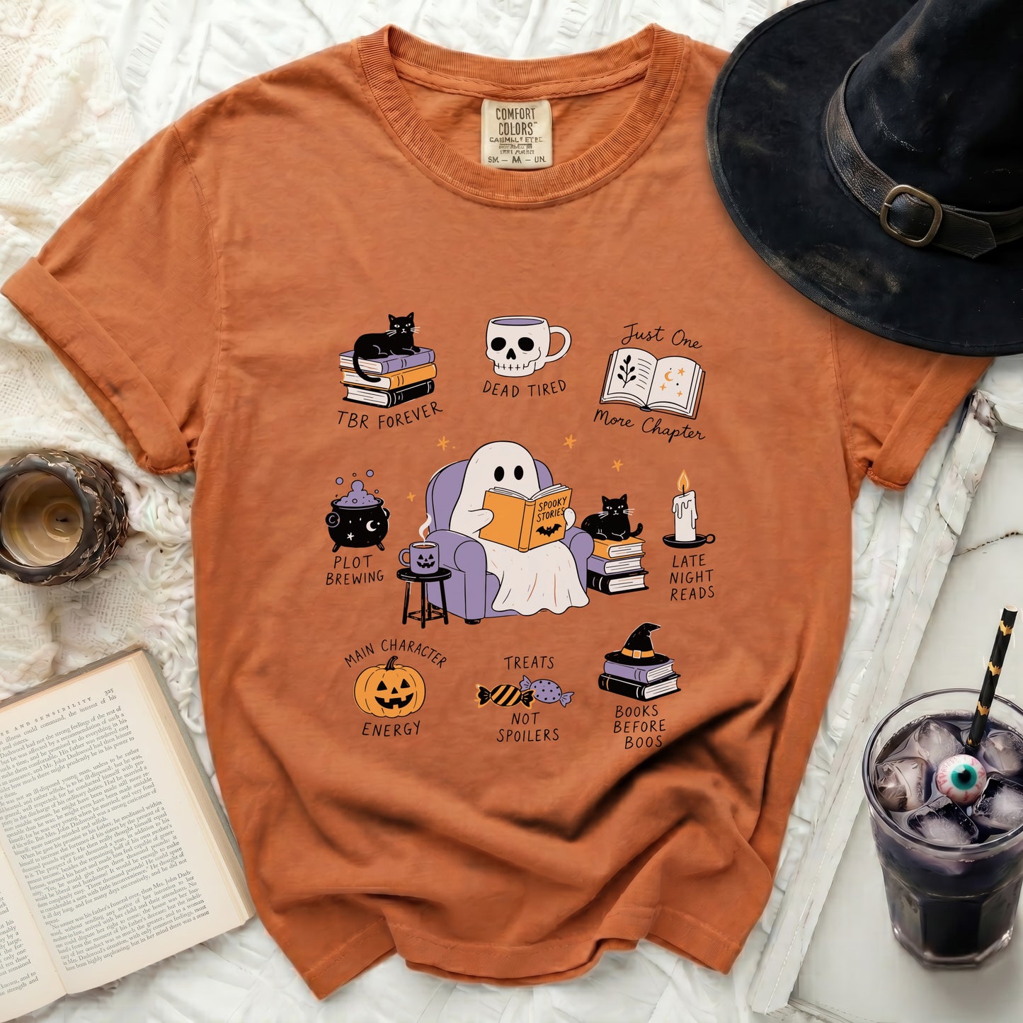 Orange t-shirt with a ghost reading a book and Halloween-themed icons.