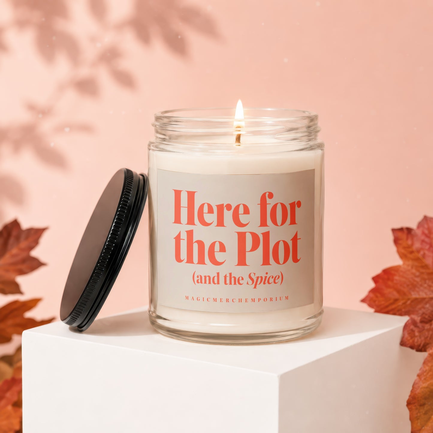 Glass candle with lid off, labeled "Here for the Plot (and the Spice)".